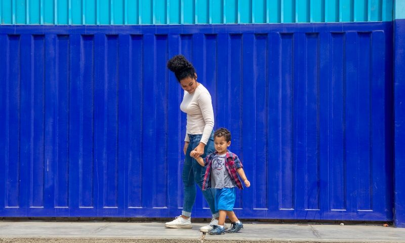 Kimberly y su hijo Matías caminando juntos por la vereda en Trujillo, Perú Prisma ONG