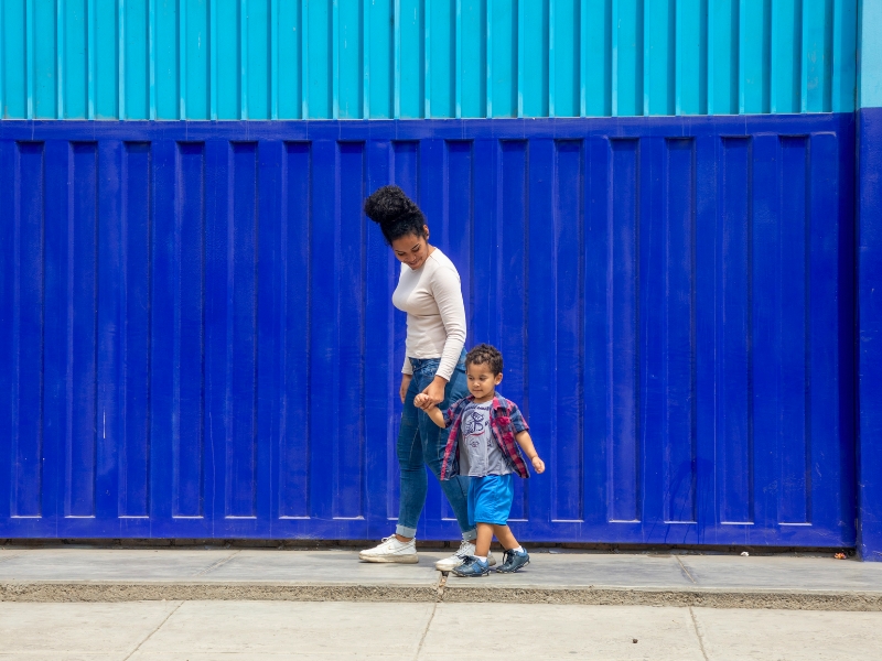 Kimberly y su hijo Matías caminando juntos por la vereda en Trujillo, Perú Prisma ONG