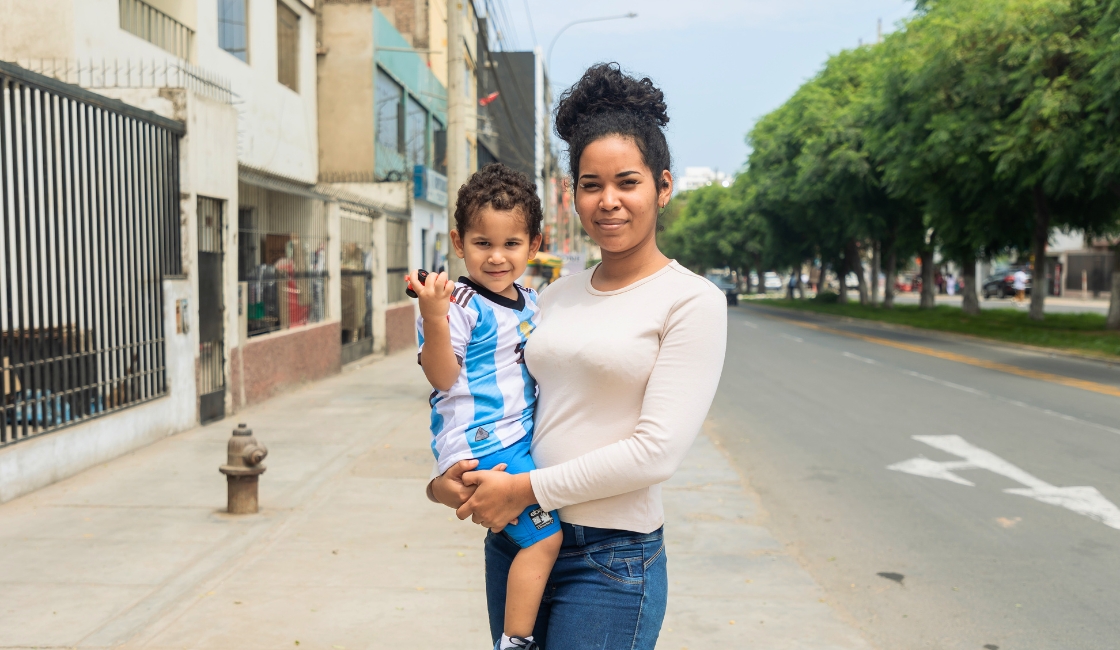 Kimberly, madre venezolana migrante, junto a su hijo pequeño en una calle de Trujillo