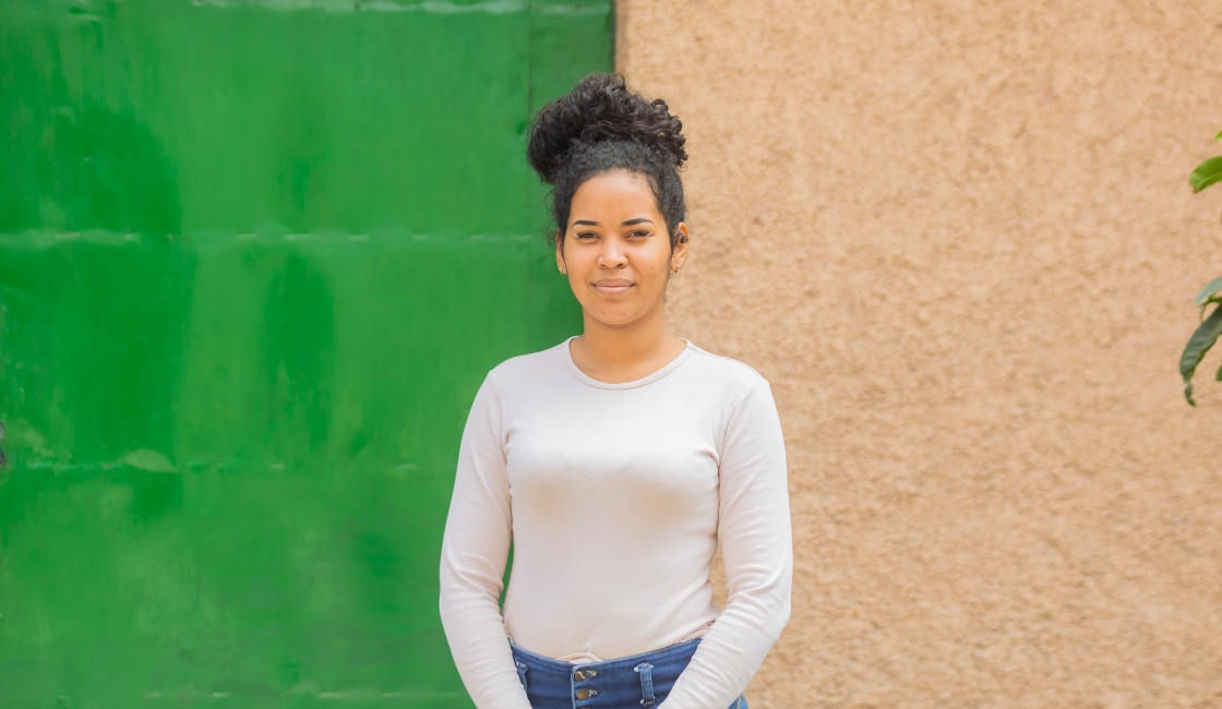 Retrato de Kimberly, mujer venezolana migrante, frente a una pared verde en Trujillo Prisma ONG