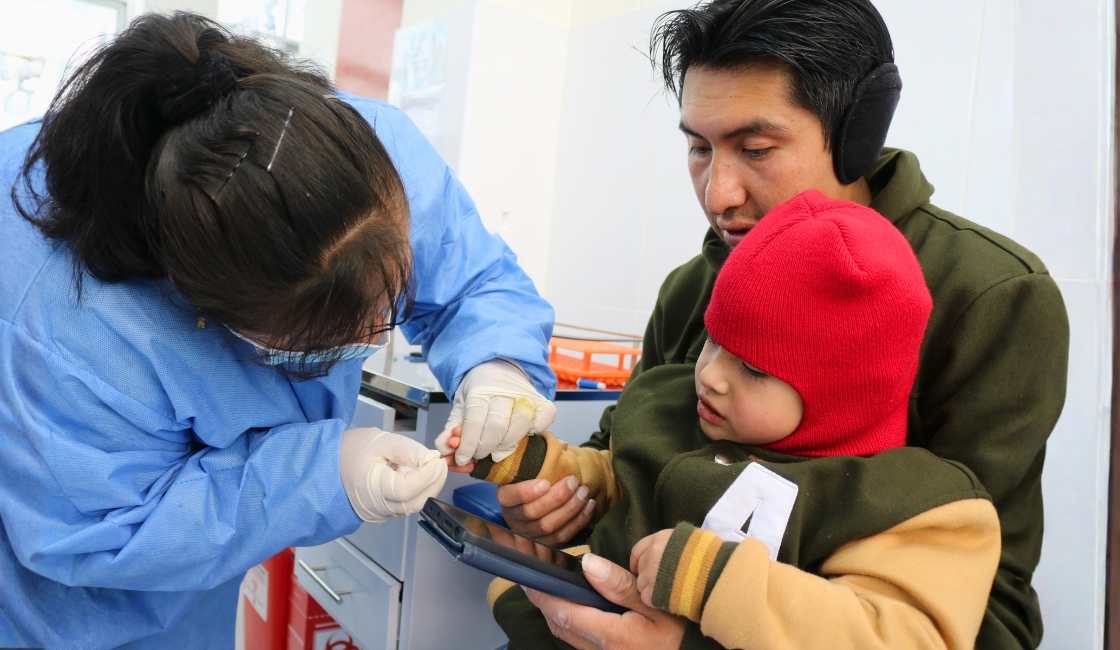 Personal de salud realiza tamizaje de anemia a un niño en un establecimiento de salud.